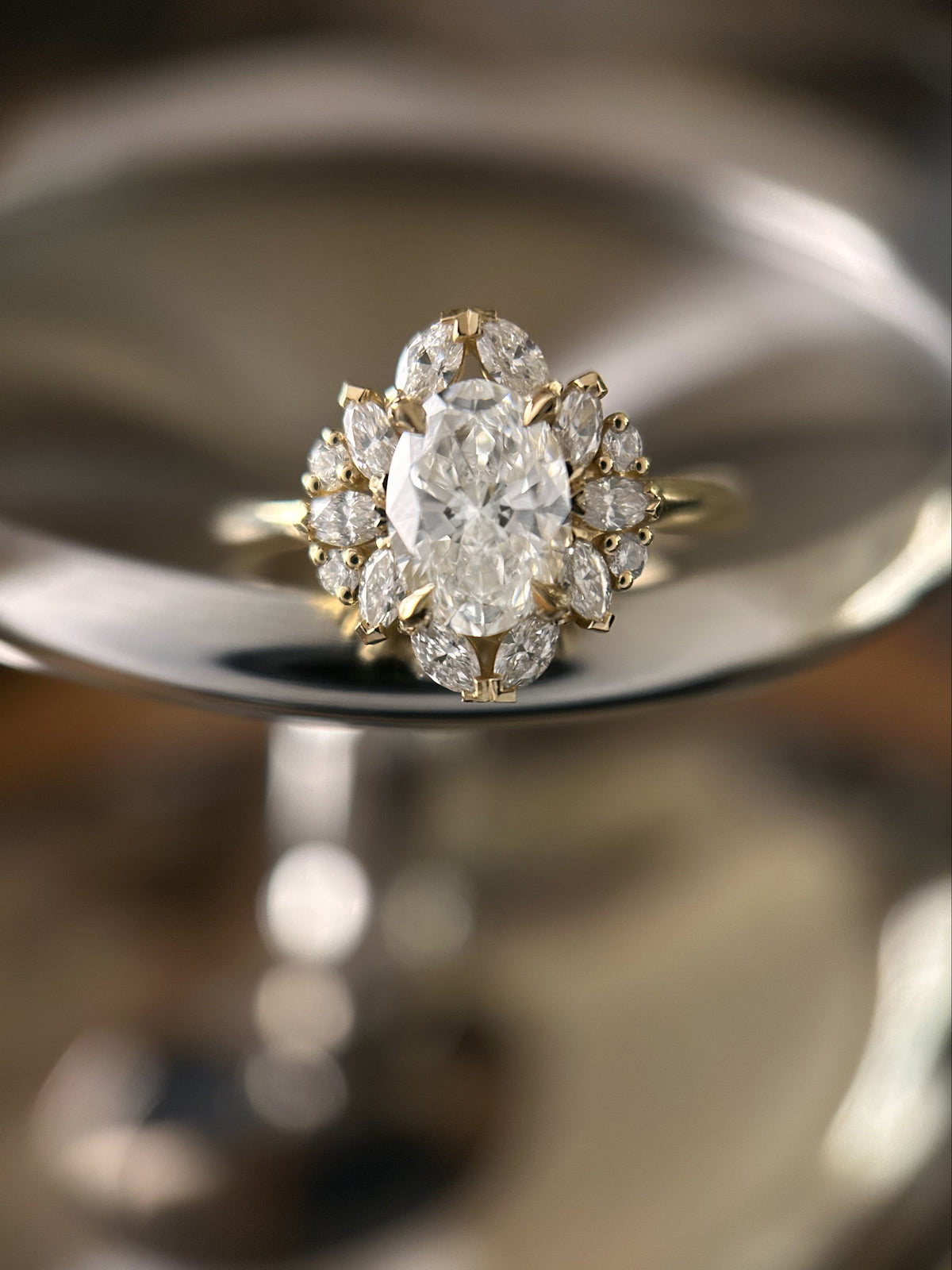 Bague de fiançailles en or jaune avec diamant central taille ovale entouré de diamants navette et ronds.