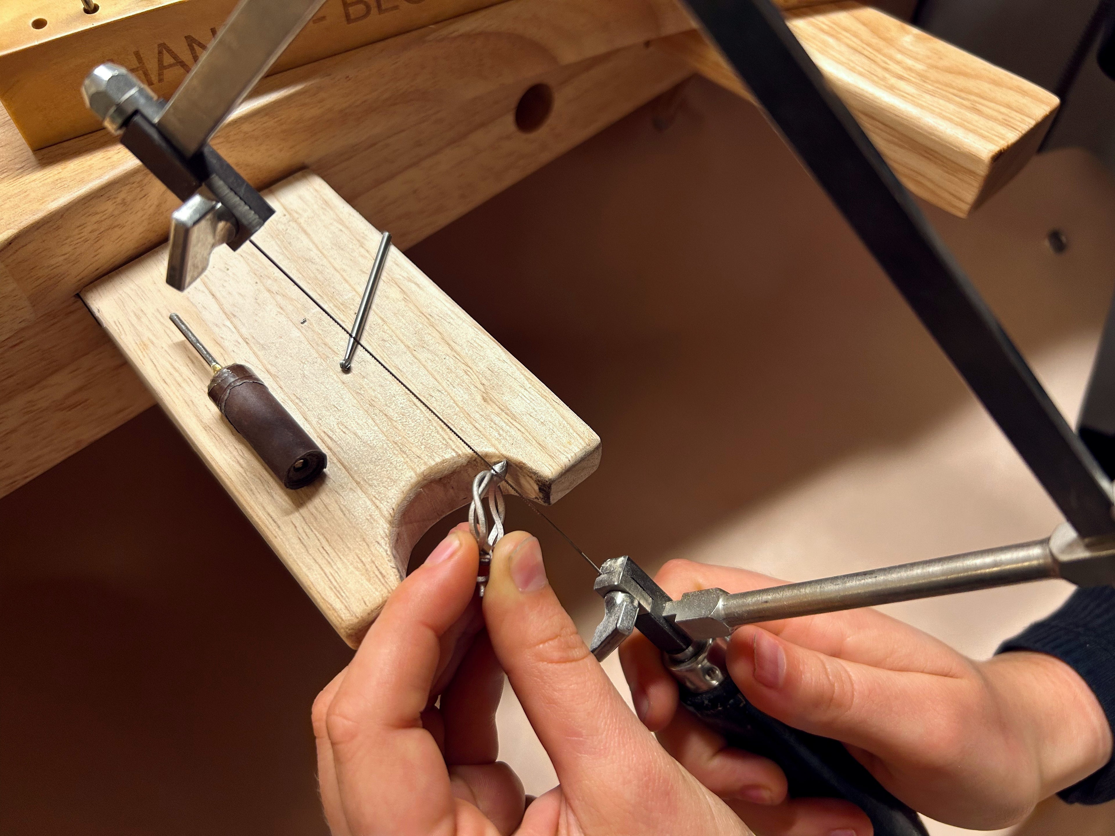 travail d'un artisan joaillier à la cheville sur une bague de fiançailles en or blanc et saphir