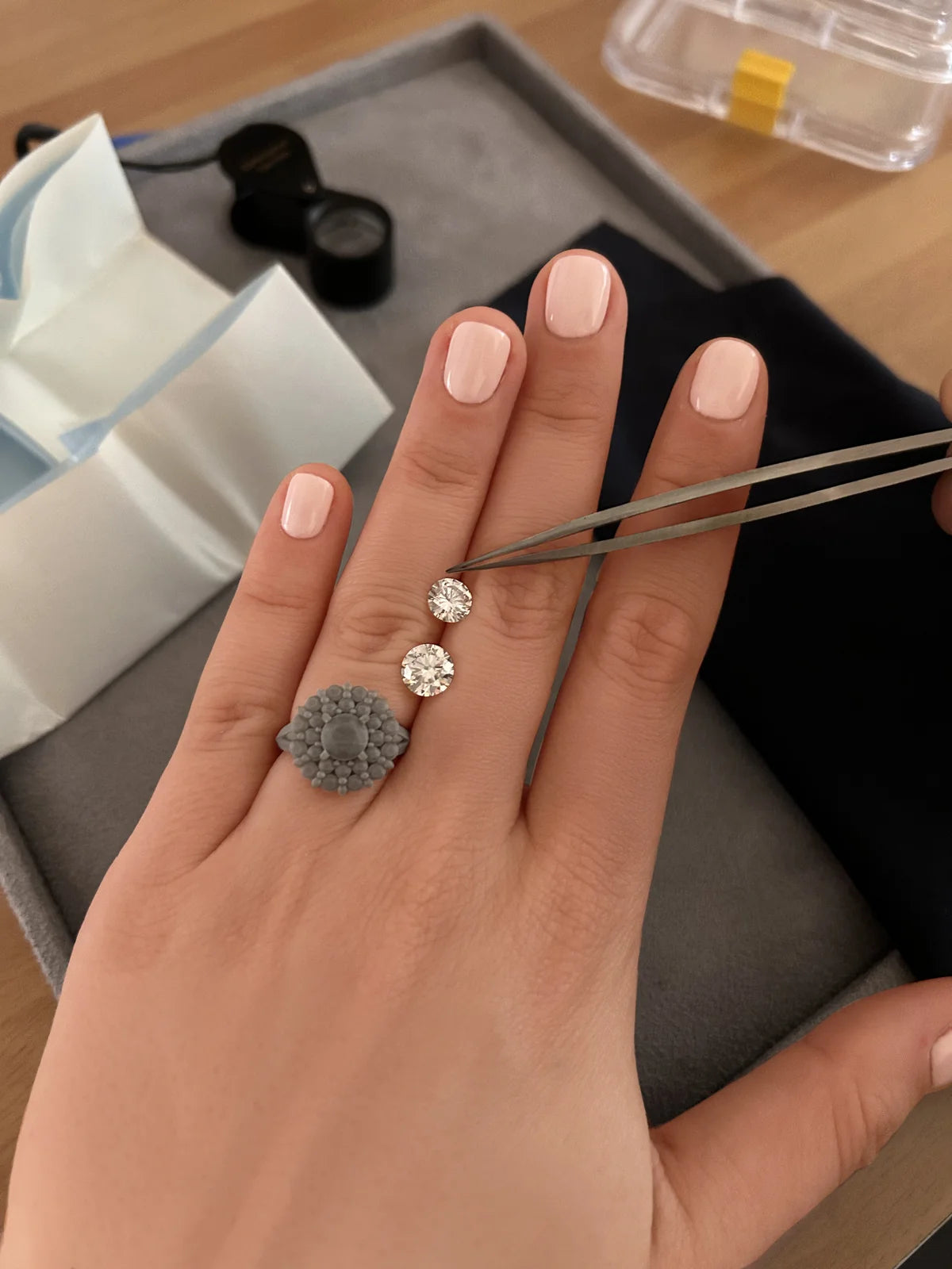 Diamants posés sur la main d’une cliente pour choisir la pierre centrale d’une bague de fiançailles sur mesure