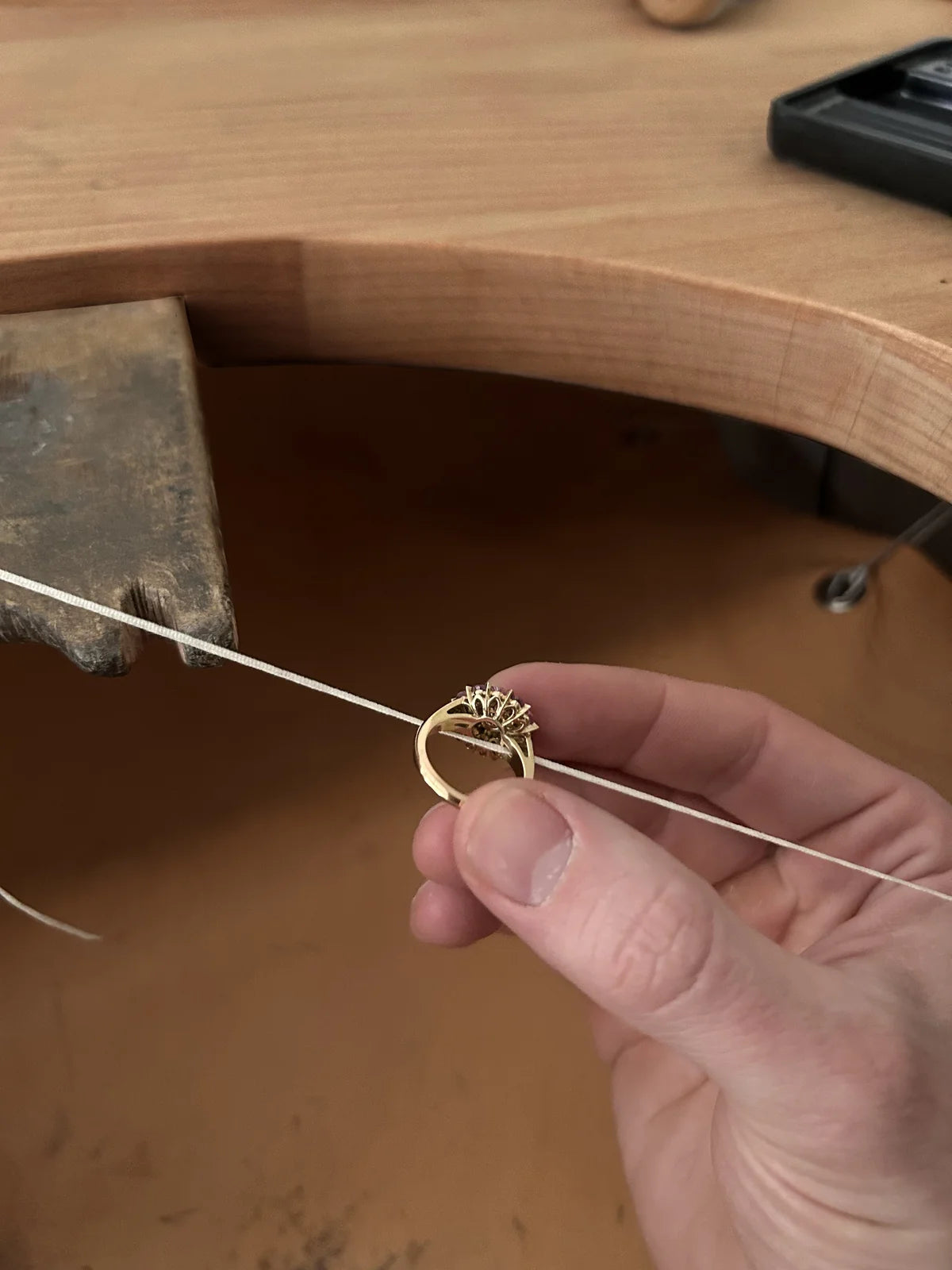 Joaillier tenant une monture de bague en or pendant la fabrication sur l’établi d’un atelier de joaillerie